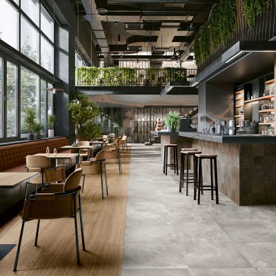 Restaurante moderno com chão cerâmico Recer: efeito madeira Opal Honey e cimento Metalcrete Warm Silver e Corten