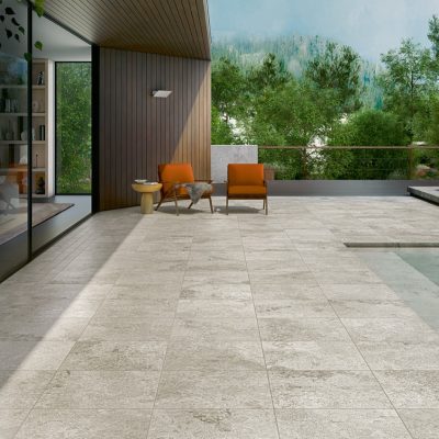 Cerâmica com efeito de pedra natural Rapolano Grey da Recer, junto à piscina de um pátio elegante.
