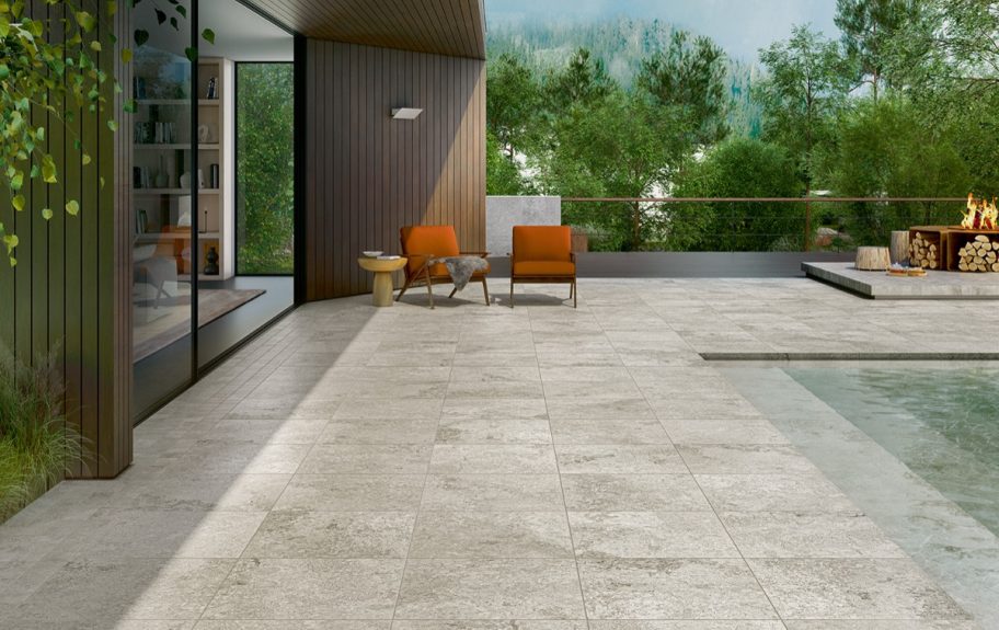 Cerâmica com efeito de pedra natural Rapolano Grey da Recer, junto à piscina de um pátio elegante.
