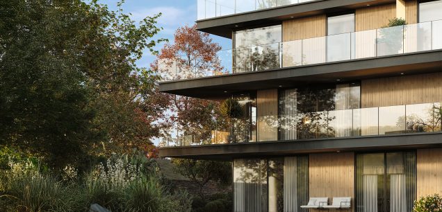 Building facade with Legacy Oak Ripple cladding creating a vertical ribbed wood effect, showcased on modern balconies with large glass panels and surrounded by landscaped greenery. Ideal architectural application of Recer ceramic wood look tiles.